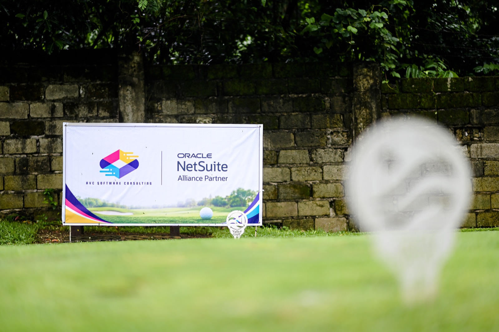 AVC Software Consulting and Oracle NetSuite sponsor banner beside a golf ball on the tee