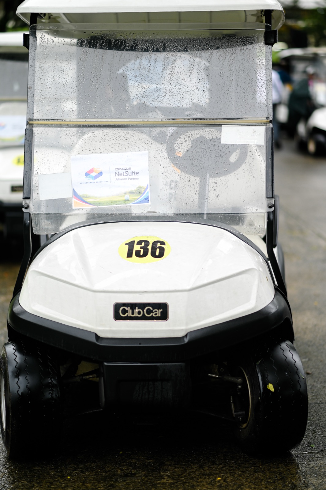 A golf cart bearing AVC Software Consulting and Oracle NetSuite signage in the rain